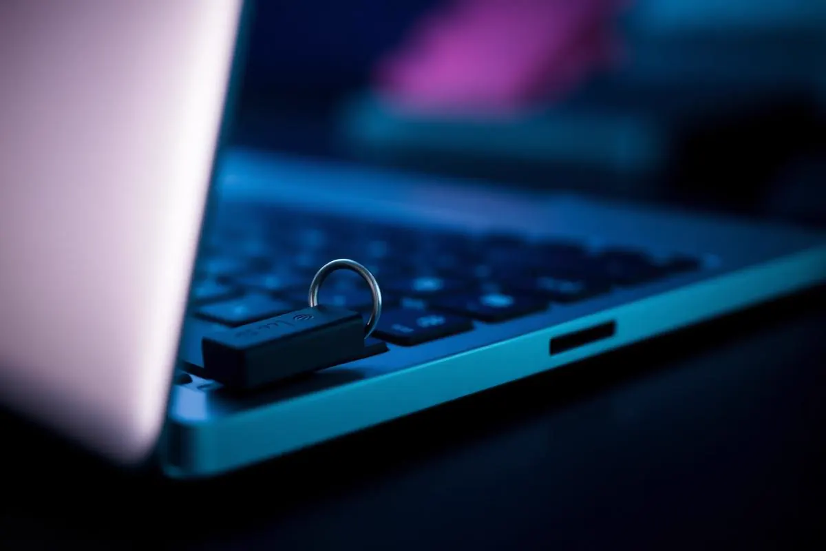 Macro close-up of a physical security key next to a laptop keyboard on a dark desk surface